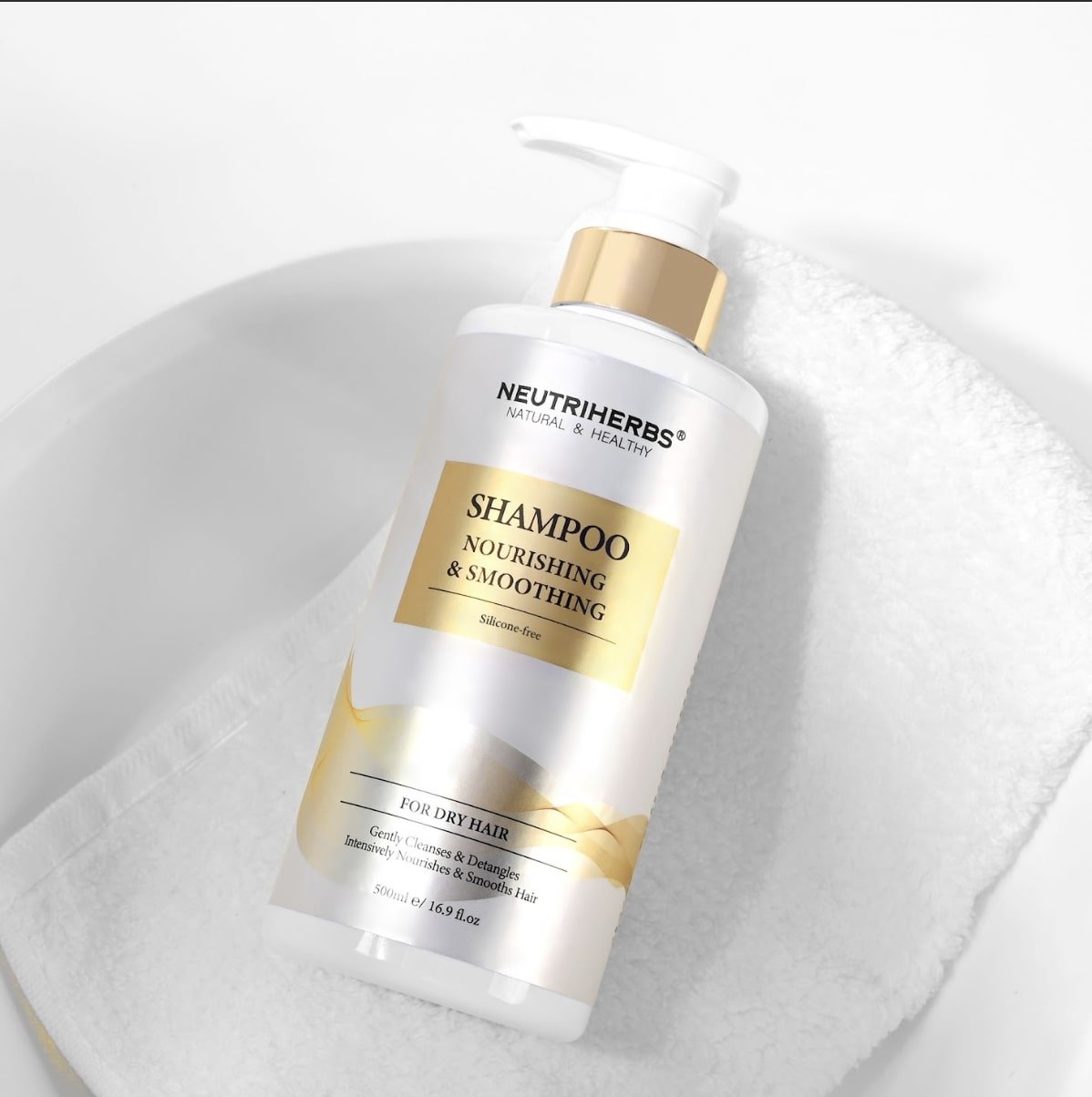 Maitinamasis šampūnas sausiems plaukams šalia balto rankšluosčio